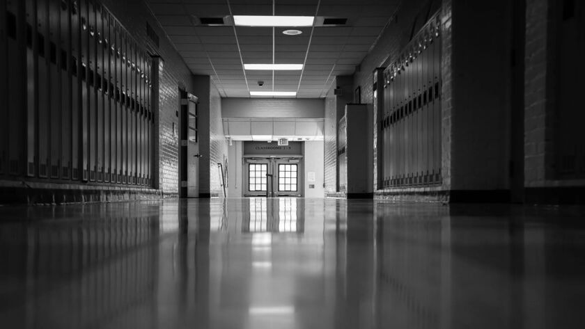 Corredor vazio de uma escola pública com luz natural entrando pelas janelas, portas fechadas e atmosfera silenciosa que transmite abandono e passagem do tempo